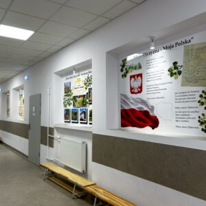 Szkolny korytarz z tablicami na pleksi przedstawiającymi symbole Polski oraz najważniejsze miejsca gminy Wądroże Wielkie