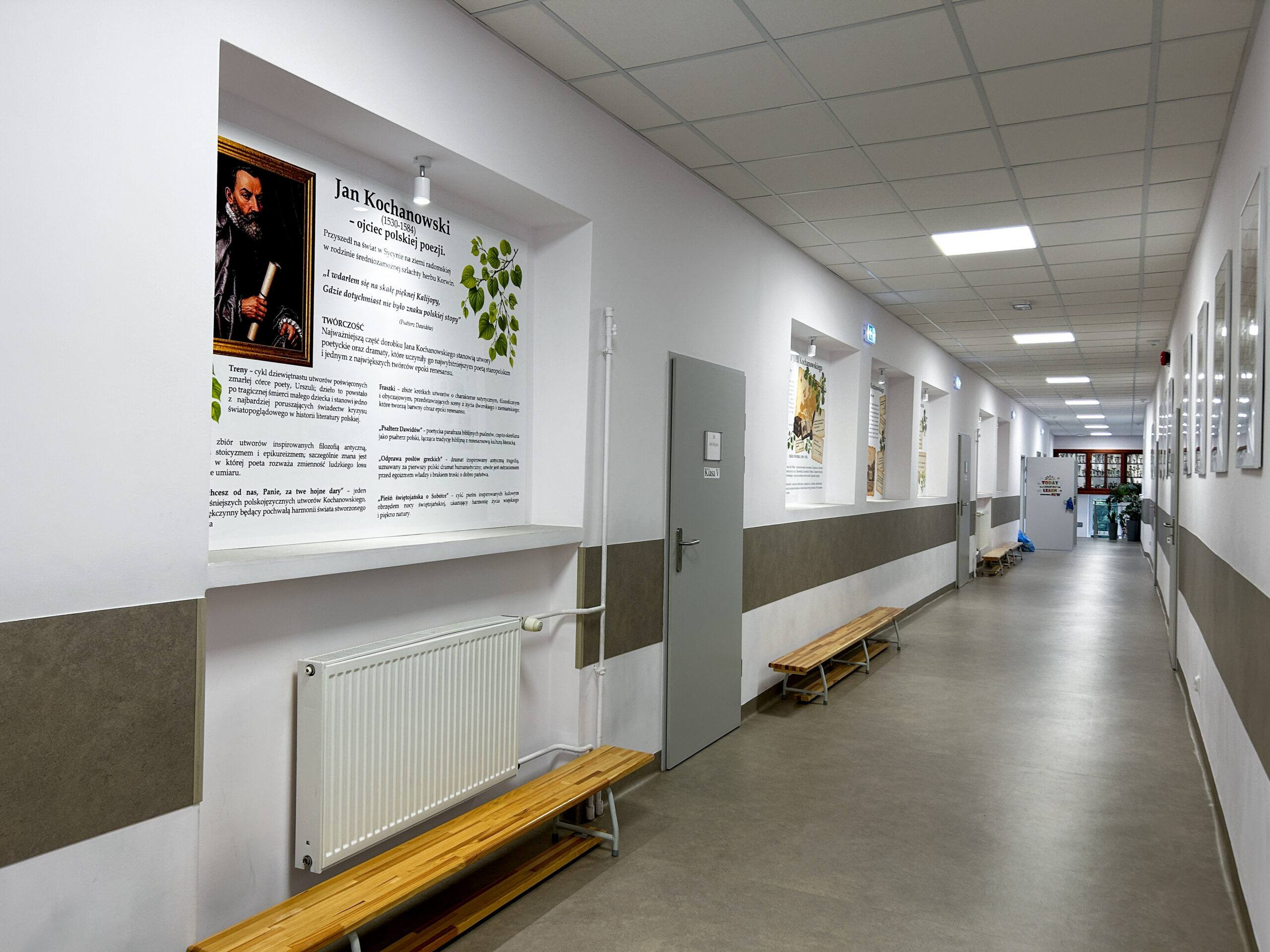 Korytarz Szkoły Podstawowej w Wądrożu Wielkim z tablicami edukacyjnymi na pleksi poświęconymi Janowi Kochanowskiemu