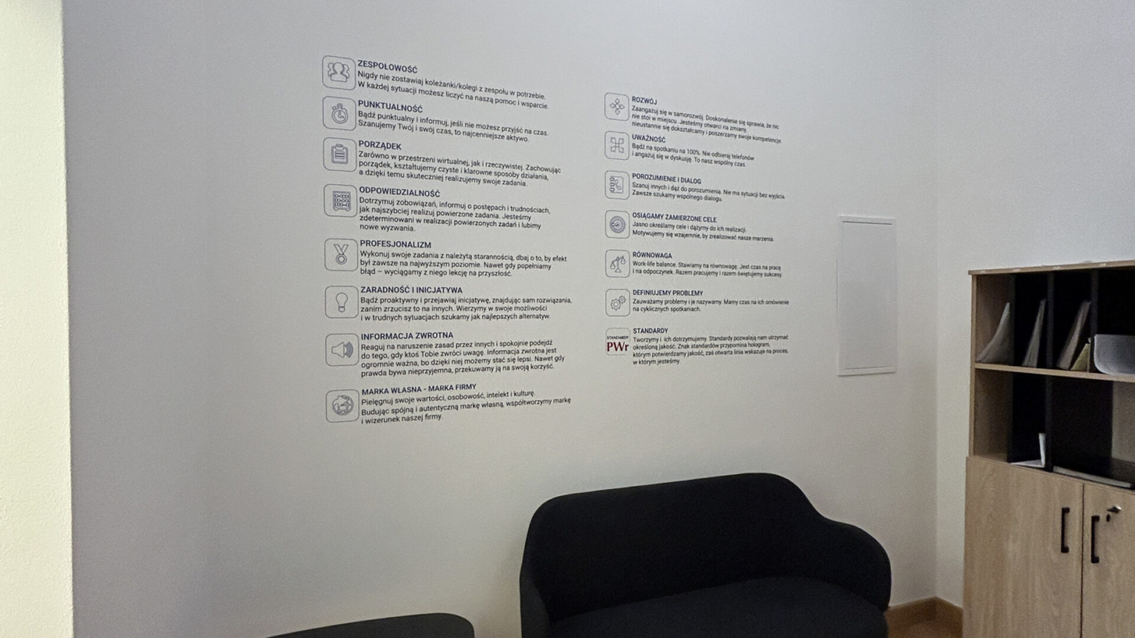 Nowoczesne wnętrze z minimalistycznym drukiem ściennym UV przedstawiającym wartości i standardy Wydziału Administracji Politechniki Wrocławskiej.