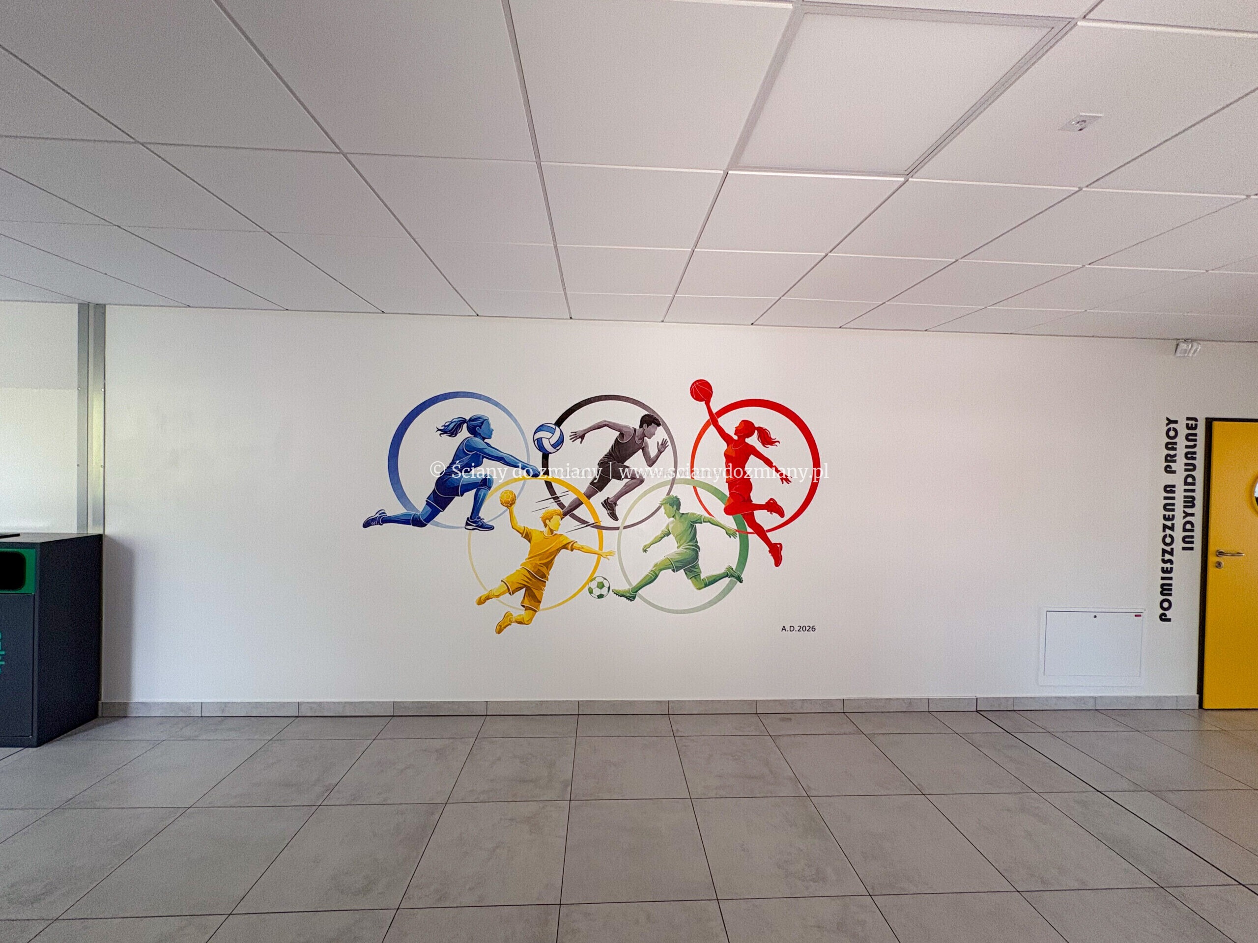 Szeroki widok gotowej sportowej grafiki w korytarzu przed salą gimnastyczną w Środzie Śląskiej